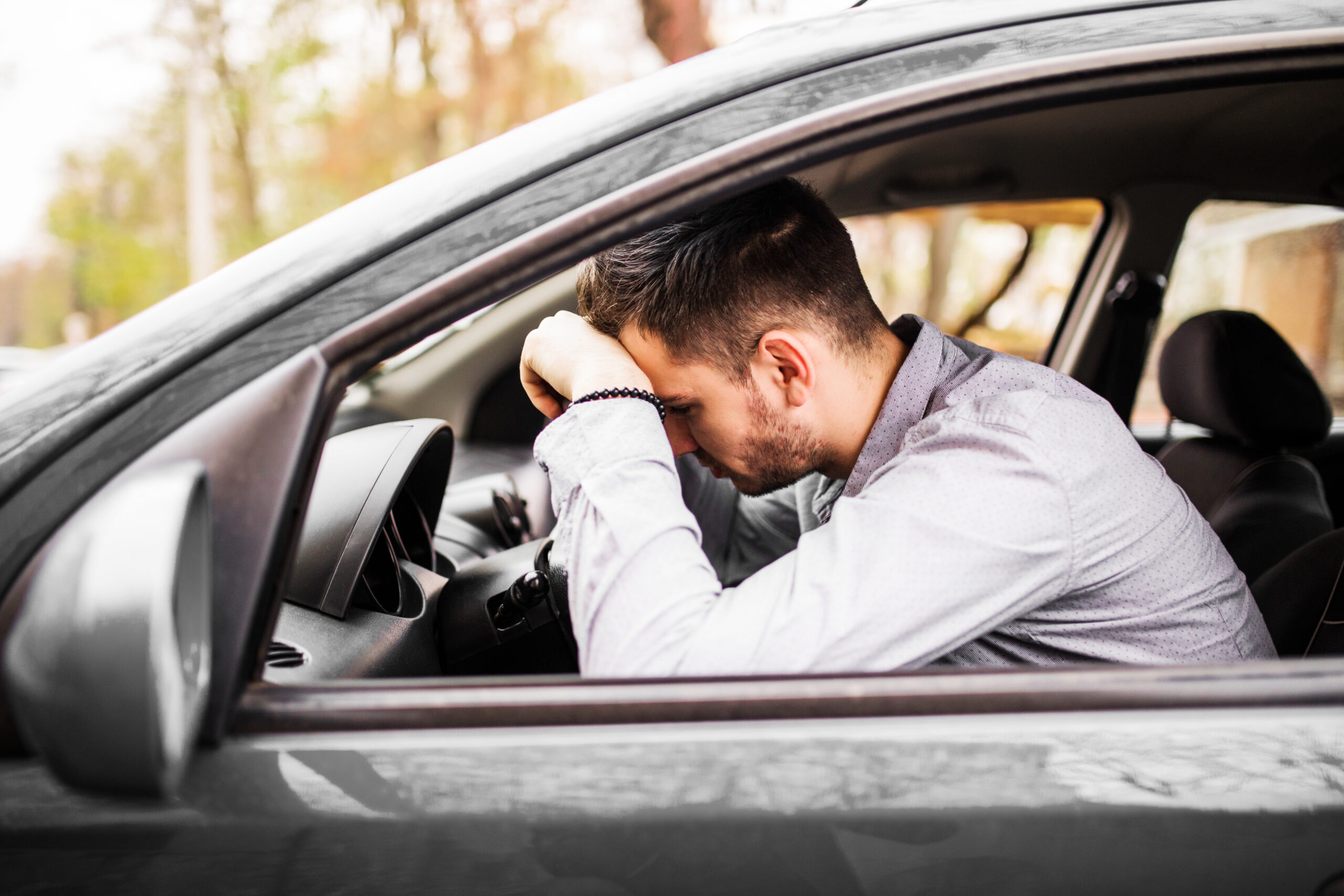 Young man sitting in car very upset and stressed after hard fail